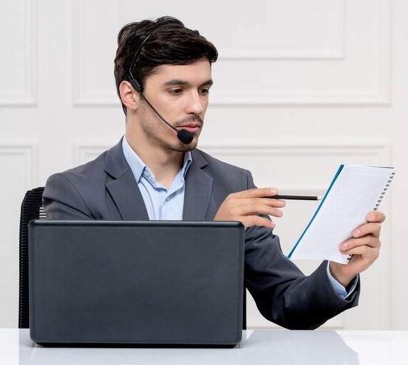 customer-service-cute-guy-grey-suit-with-computer-headset-pointing-his-notes_140725-164176